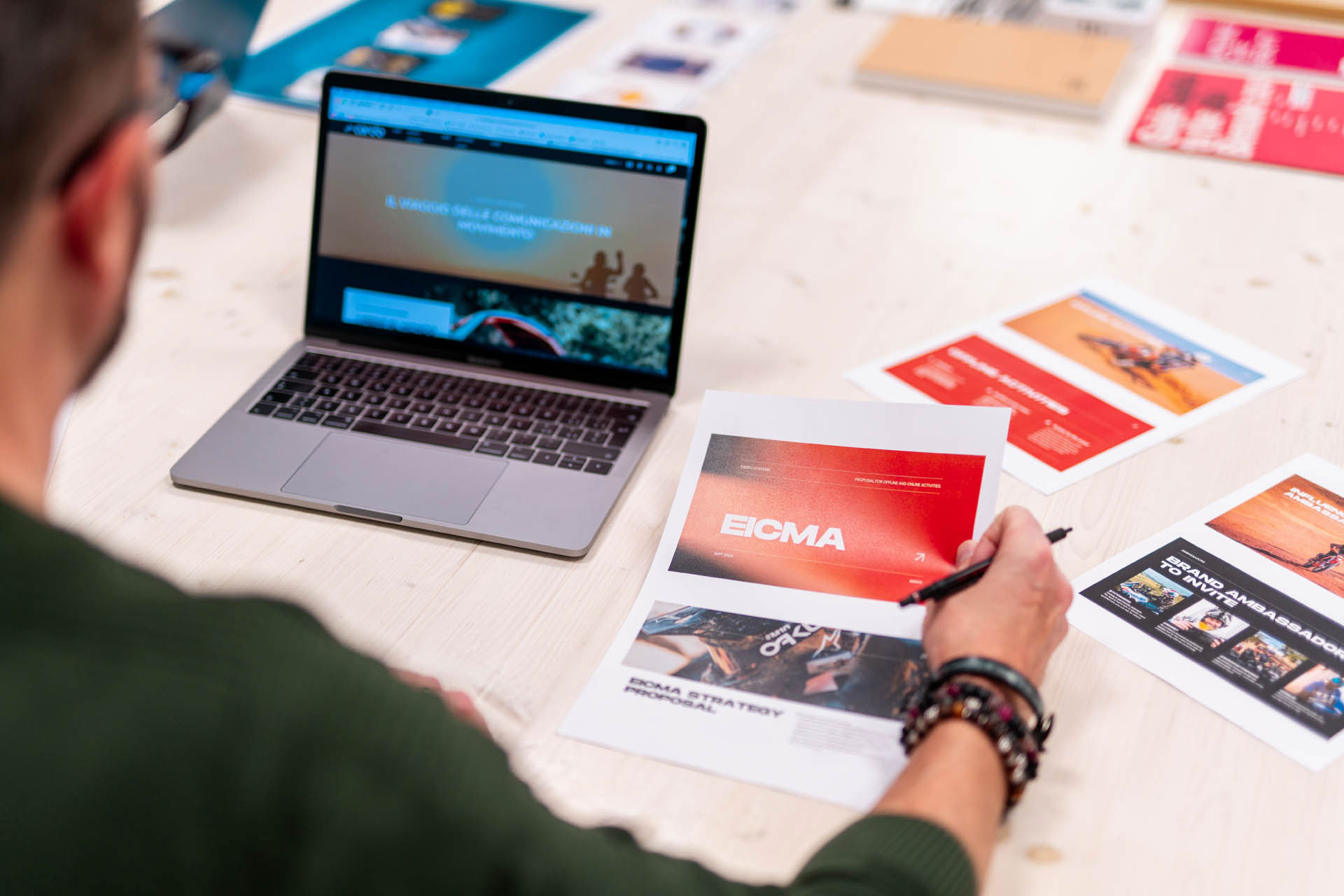 Immagine di una persona che lavora al portatile mentre guarda la copy di un layout grafico