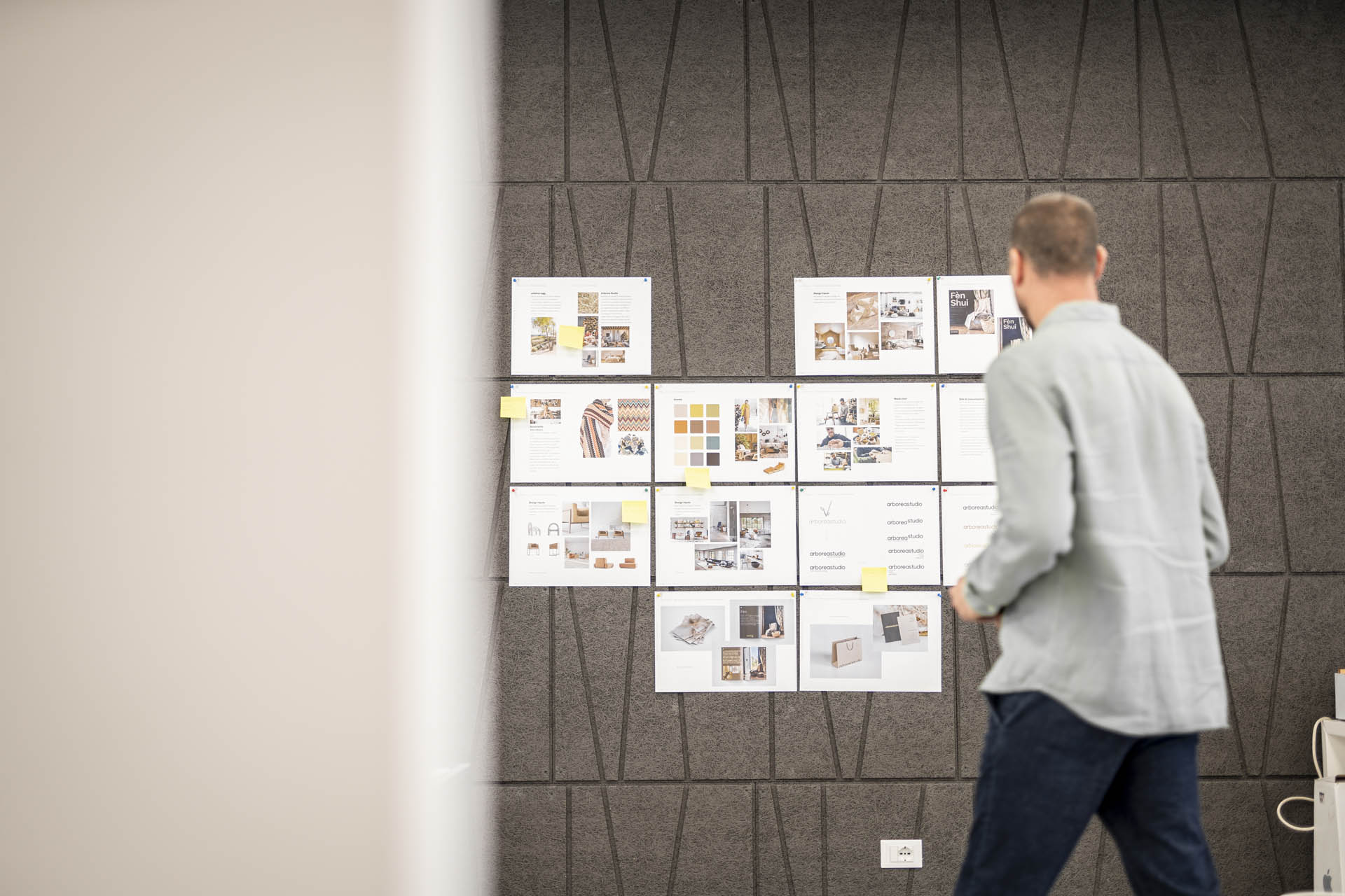 Una persona osserva delle moodboard appese a una parete per verificare la coerenza tra immagini, testi e brand