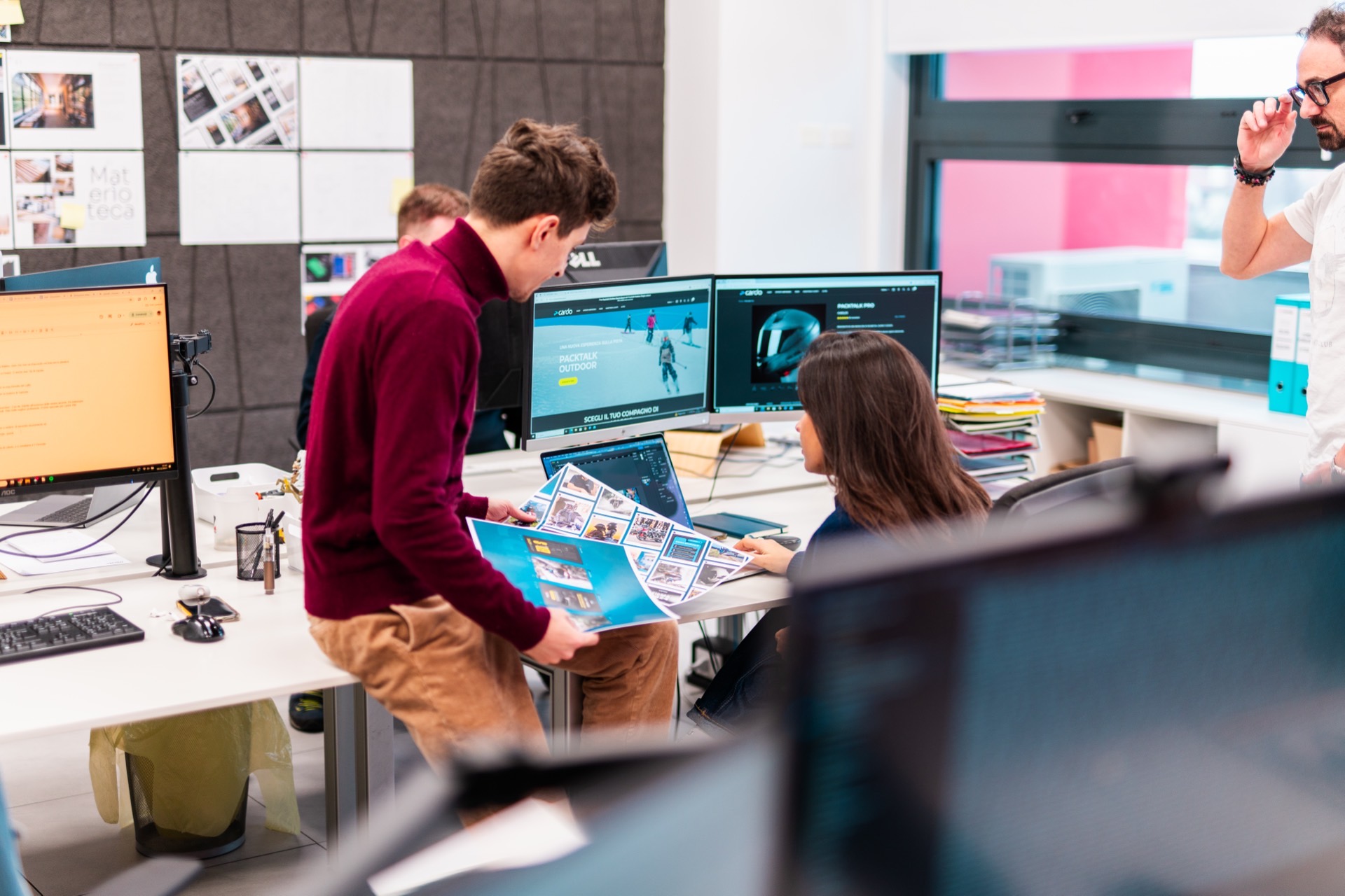 Tre persone in un ufficio guardano insieme delle stampe A3 di concept per contenuti social b2b